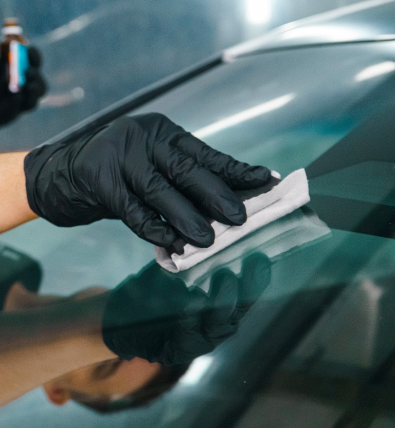 Gloved technician hand-polishing a windshield